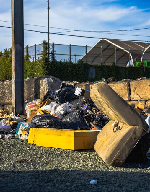 Several blue plastic rubbish bags, filled and tied at the tops, are stacked on the concrete step of an exterior city building entrance. The bags appear to contain household or waste items and are posi